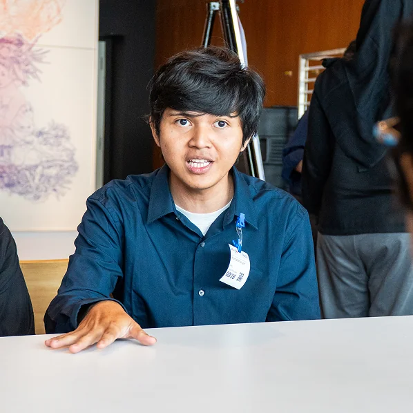 Alfian seated, speaking during a session