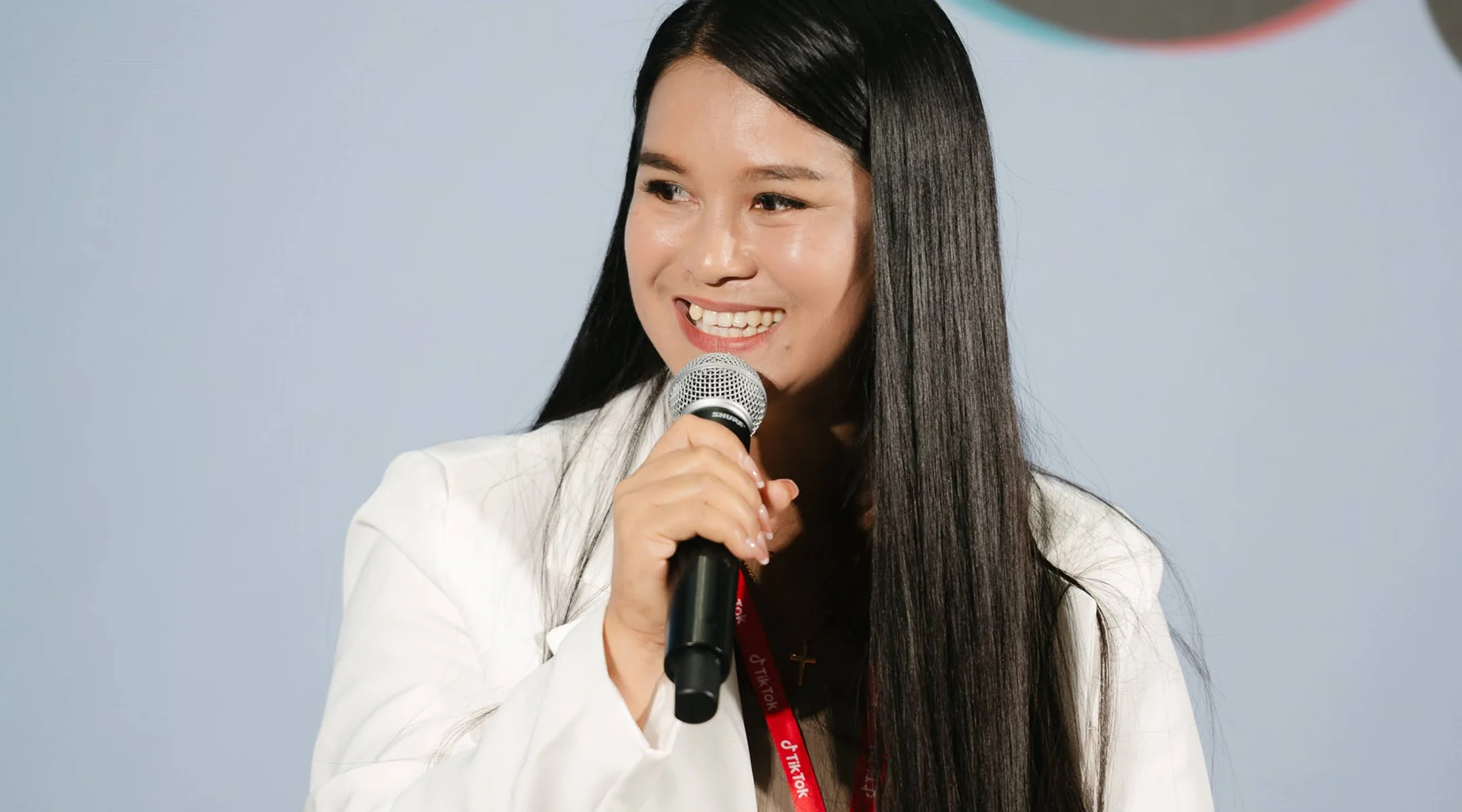 Kru Yui smiling as she speaks into a microphone at an event