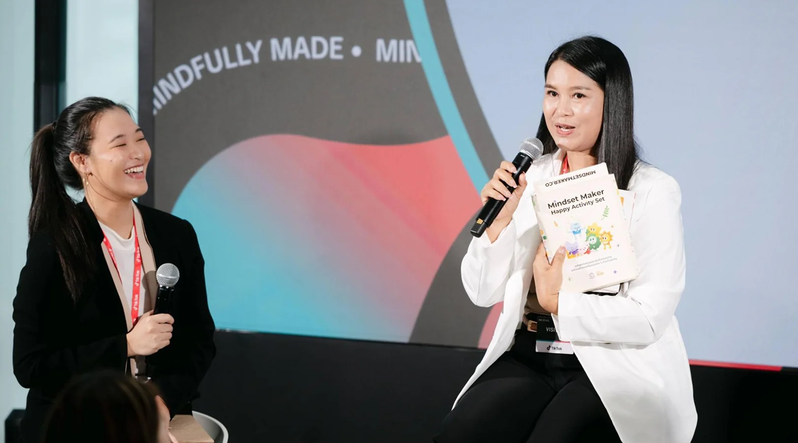 Kru Yui holding the Mindful Maker toolkit on stage during the program