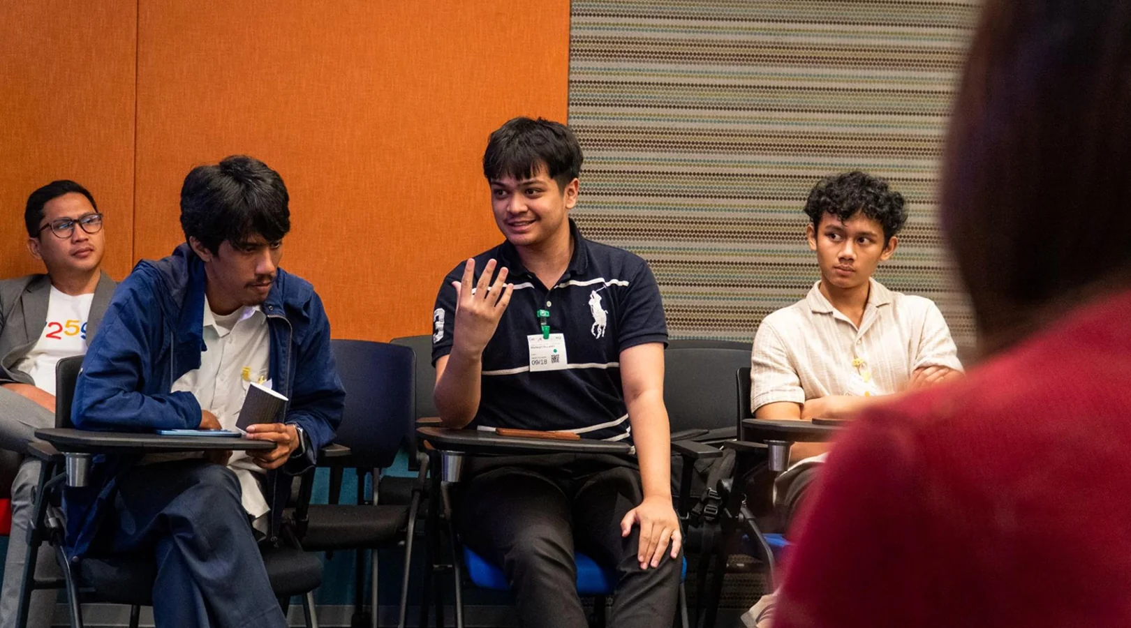 Muttaqin gesturing as he speaks while seated among other participants at the Future Feature Policy Roundtable