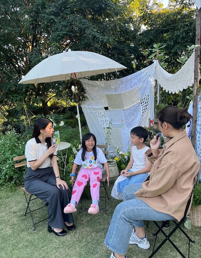 Kru Nutt interviewing two children in a garden setting