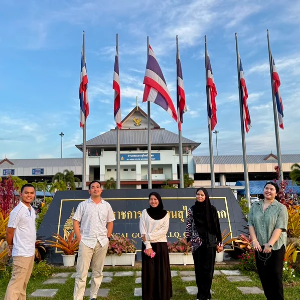 A group standing before flagpoles at a civic building