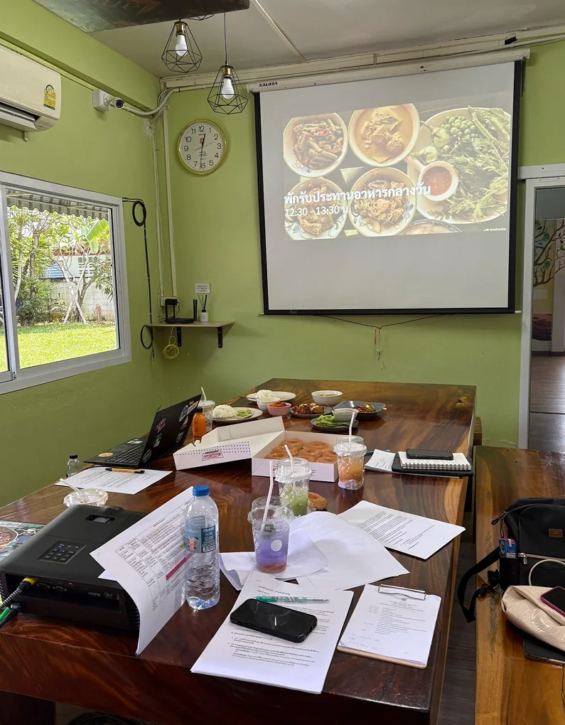 A meeting room with a projector screen and research papers spread on a table