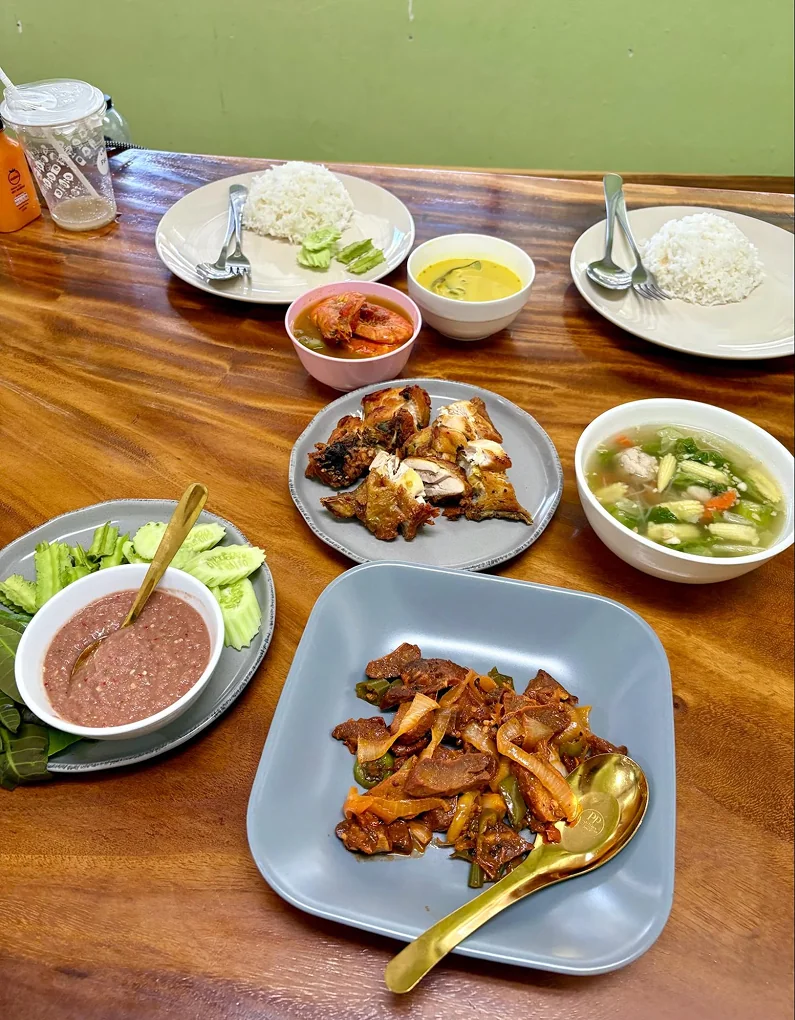 A spread of home-cooked Southern Thai dishes on a wooden table
