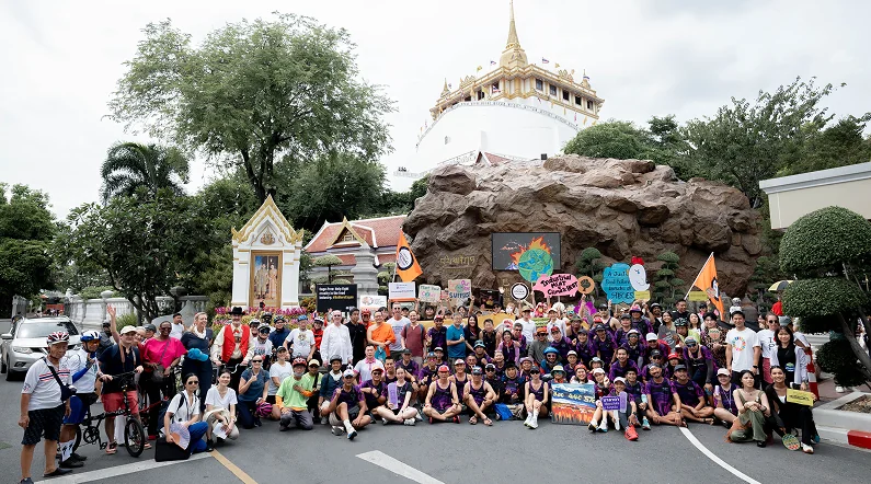 A large group photo of parade participants in front of a temple