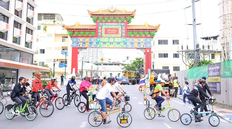 Cyclists setting off past a decorated Chinatown gateway